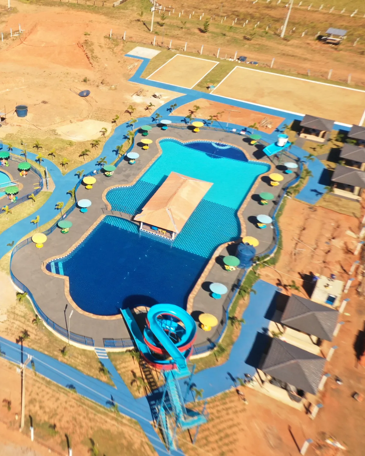 Vista aérea da piscina principal do Águas Clara Resort, com quiosque central, guarda-sóis e toboágua